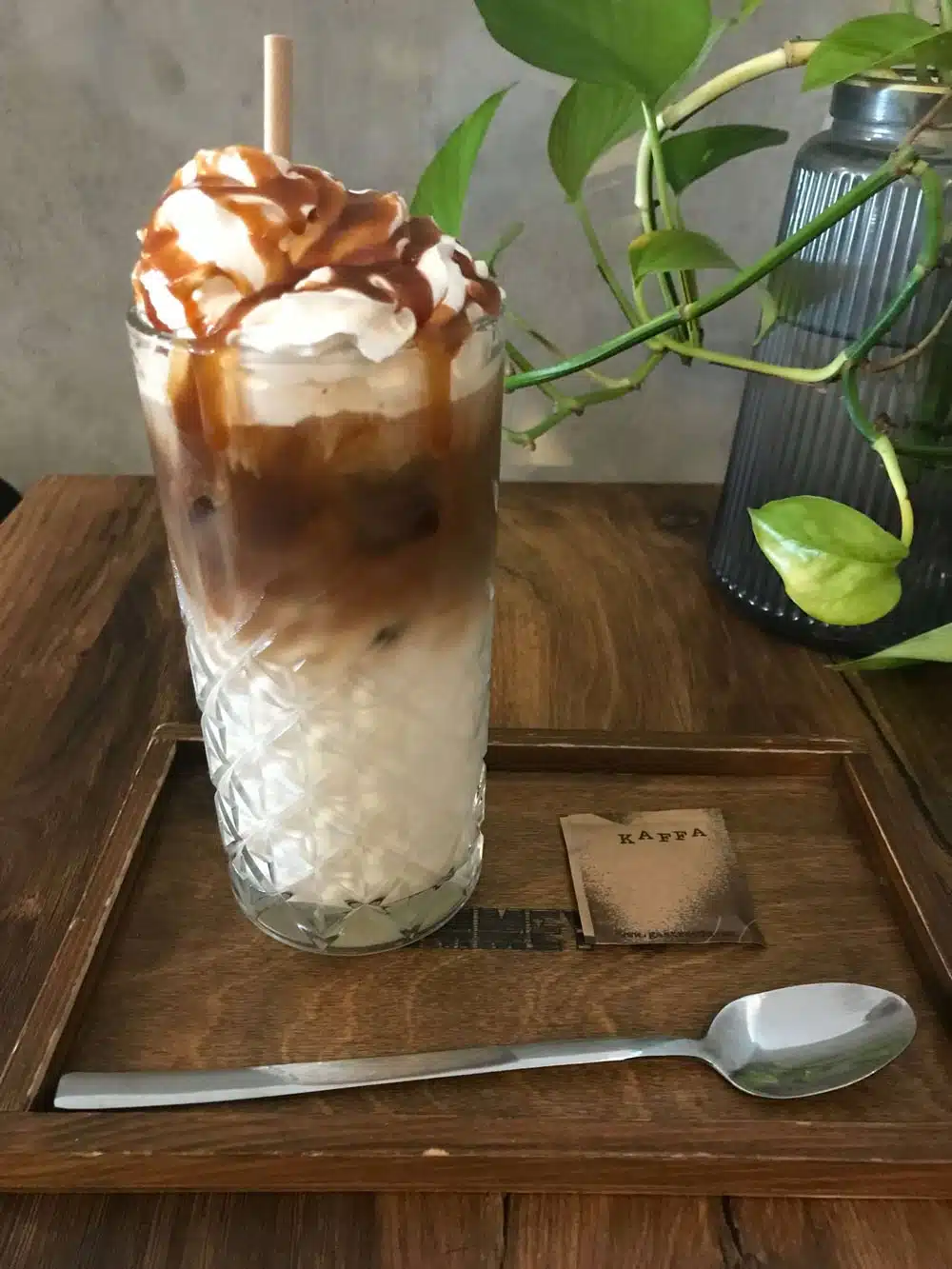 Indulge in a clear glass of cappuccino, elegantly crowned with a swirl of luscious whipped cream and drizzled with rich caramel sauce.